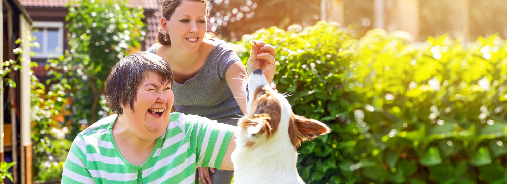 two women are smiling while feeding the dog